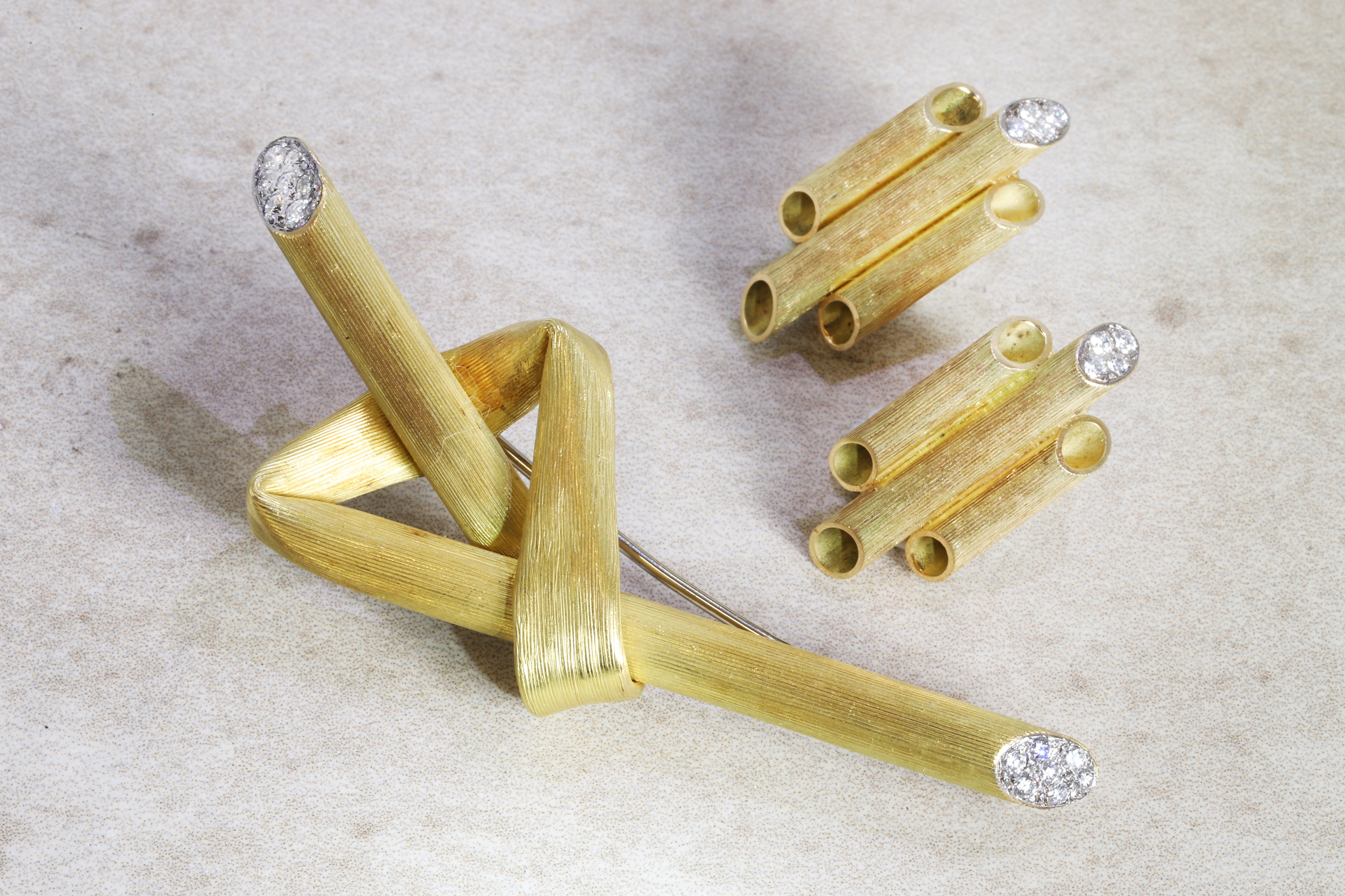 an 18ct gold and diamond brooch, c.1970s, modelled as a stylised straw folded into a knot, in textured gold with pavé diamond terminals (estimate £3,000-5,000), and a pair of 18ct gold and diamond tube earrings